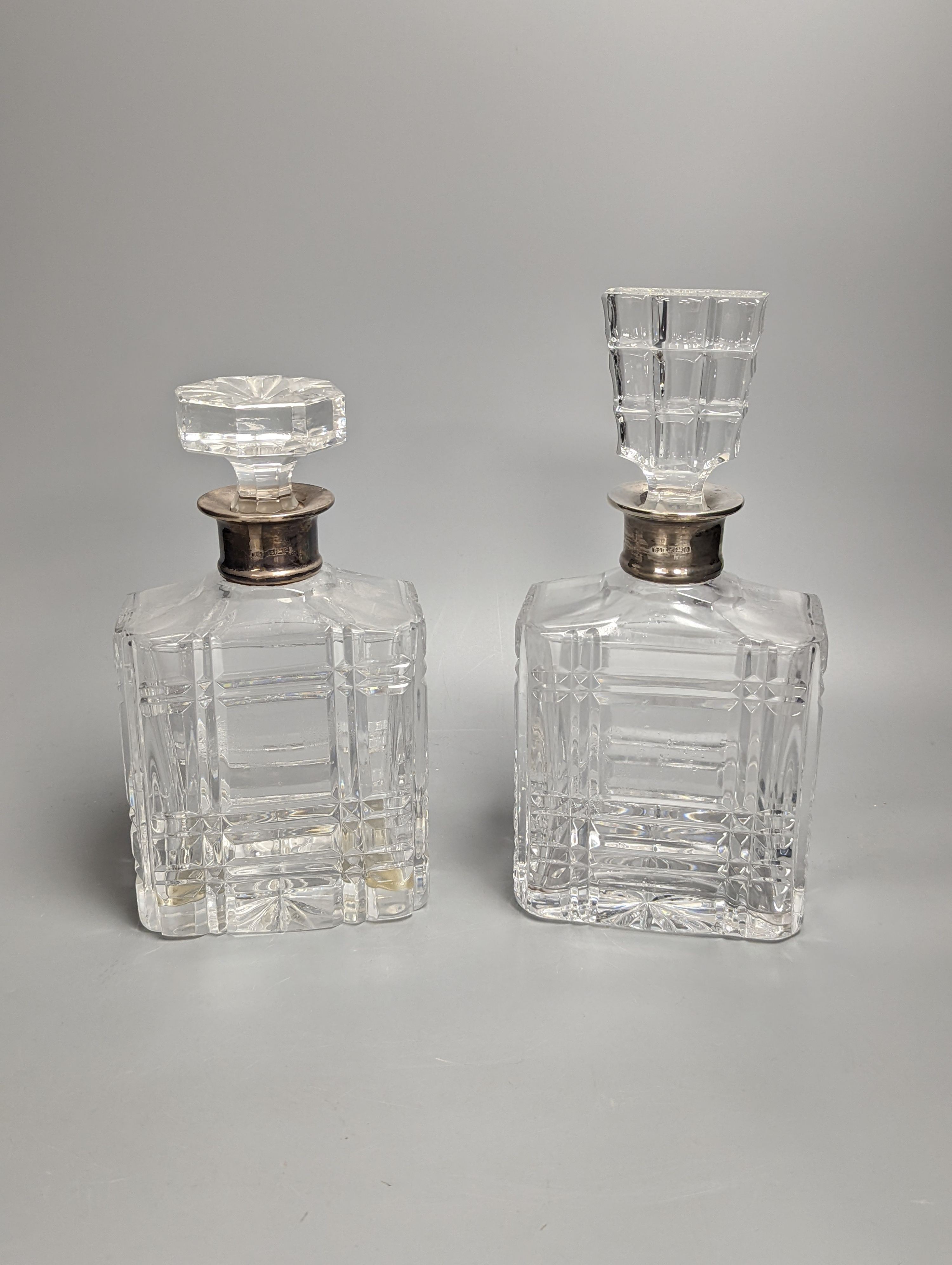 A pair of silver mounted cut glass decanters, with mis-matched stoppers